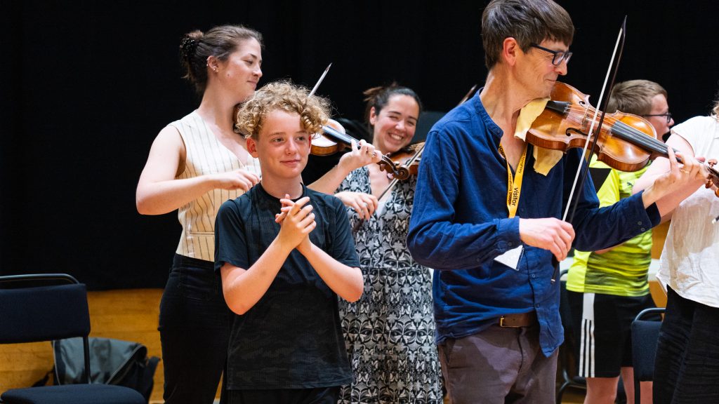 A student participating in an open workshop with violinist Matthew Truscott and other members of the OAE