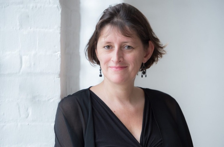 Catherine Rimer wears black and smiles in front of a white background.