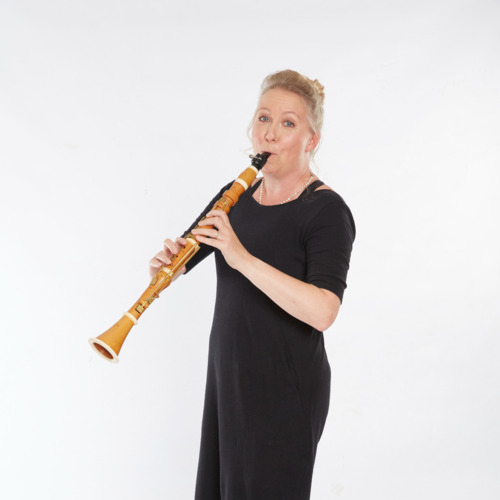 Katherine Spencer wears all black. She turns to face the camera as the holds her clarinet to her mouth and plays.